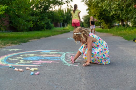 Children draw with chalk on the asphalt. Selective focus. kid.