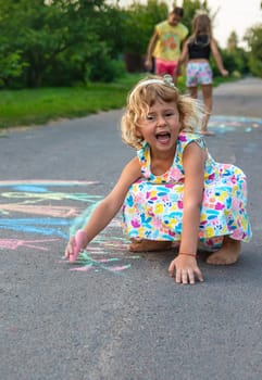 Children draw with chalk on the asphalt. Selective focus. kid.