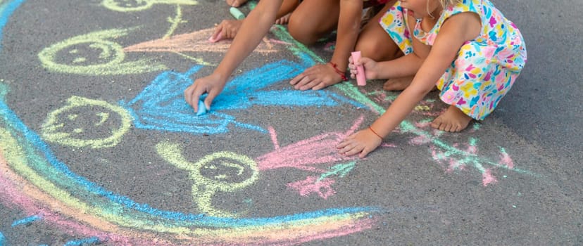 Children draw with chalk on the asphalt. Selective focus. kid.
