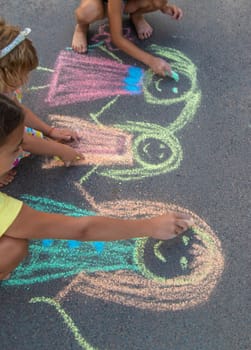 Children draw with chalk on the asphalt. Selective focus. kid.