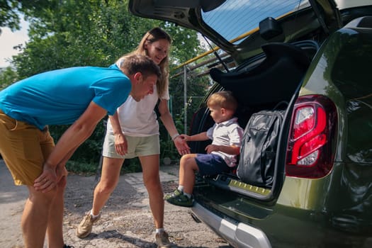 A cheerful family happily packs their car for an exciting outdoor adventure, engaging joyfully with their young child