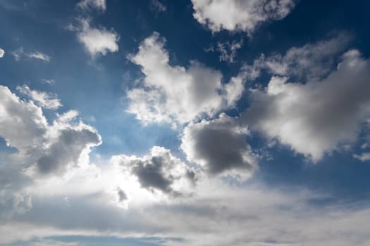 The suns rays are breaking through the cumulus clouds in the electric blue sky, creating a tranquil atmosphere in the natural landscape.