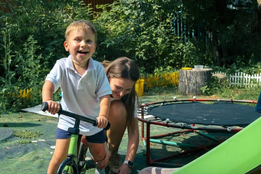 In a vibrant garden, a cheerful child rides a bike as an adult lends a hand, creating a joyful scene