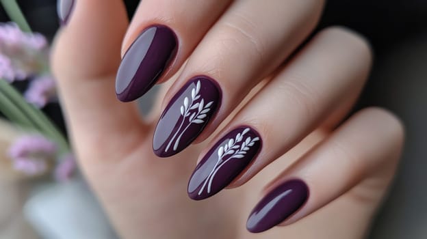 Close-up of a woman's hand showcasing elegant botanical nail art on dark purple nails. the intricate design features delicate white plant motifs, creativity and beauty in personal grooming. perfect for fashion and art contexts.