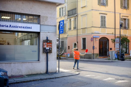 Cremona, Lombardy, Italy - November 7th 2024 Construction worker managing traffic flow with stop sign, ensuring safety near a construction site in an urban area