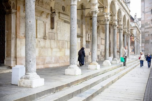 Cremona, Lombardy, Italy - November 7th 2024 An elderly woman walks with a cane under the arcades of the palazzo della ragione in padua, italy, a historic landmark