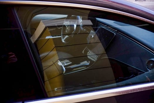 Cremona, Lombardy, Italy - November 7th 2024 Luxurious vehicle interior glimpsed through window, highlighting steering wheel, dashboard, and premium materials