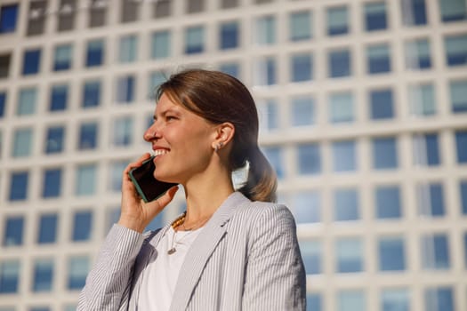 A confident woman is talking on her phone outdoors, showcasing her role in the modern business lifestyle