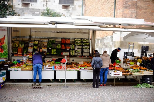 Cremona, Lombardy, Italy - November 6th 2024 Shoppers purchasing produce from a mobile greengrocer's stall at an outdoor market in italy