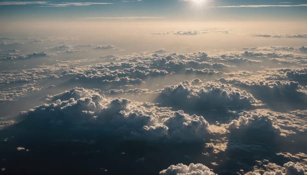 A wide shot of a sky filled with fluffy white clouds illuminated by a setting sun. Some of the clouds are darker than others, casting shadows over the lower clouds.