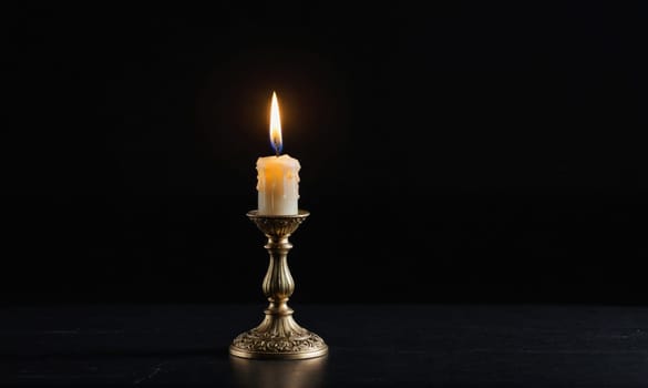 A single, white candle with a flickering flame sits in a silver candlestick on a dark surface.
