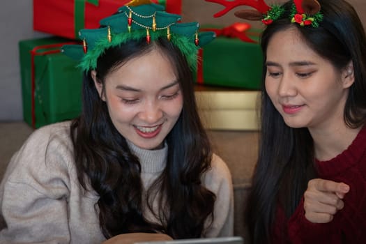 Happy lesbian couple enjoying Christmas festivities with gifts and holiday decorations in a warm, cozy atmosphere.