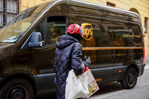 Cremona, Lombardy, Italy - November 7th 2024 Ups delivery van driver stopping to let a pedestrian cross the street in an old italian city