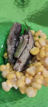 food snack, fish sprats canned, yellow corn, green plate . High quality photo