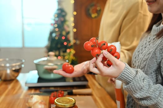 Close up of young woman choosing fresh tomatoes for a holiday dish.