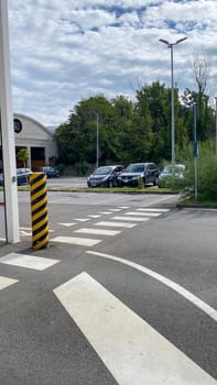 Cremona, Lombardy, Italy October 15th 2024 Pedestrian crossing with white lines and black and yellow bollard in a parking lot with cars and street lamps on a cloudy day