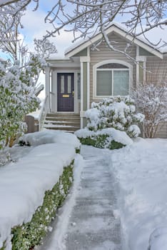 Cleaned pathway to the family residential house over front yard in snow.