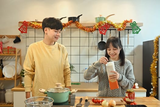 Smiling young couple preparing ingredients for a cozy holiday dinner.