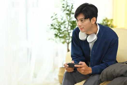 Man in casual outfit Playing video games with controller in living room.