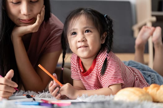 A young child learning at home with a parent, surrounded by educational materials, promoting creativity and knowledge in a cozy setting.