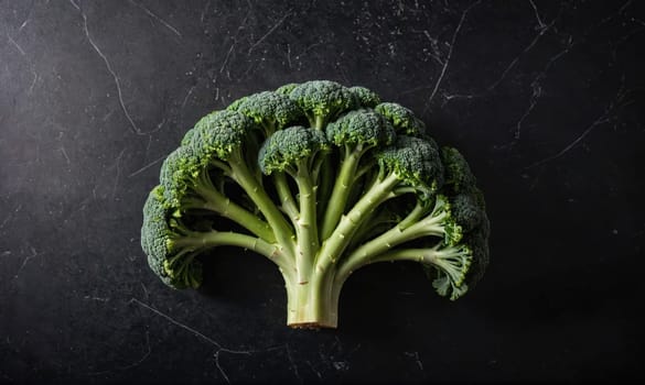 A single broccoli floret is shown on a black background, with its numerous florets spreading out from the center.