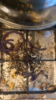 Cremona, Lombardy, Italy October 15th 2024 Food and debris covering a very dirty gas stove top with purple rubber burner covers
