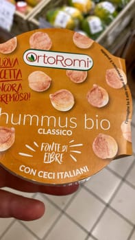 Cremona, Lombardy, Italy October 15th 2024 Close up of ortoromi classic organic hummus packaging, made with italian chickpeas and a good source of fiber, held by a customer in a supermarket