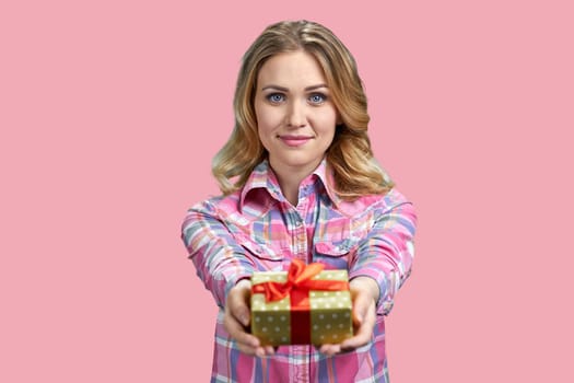 Attractive young blond woman giving a gift box. Isolated on pink background.