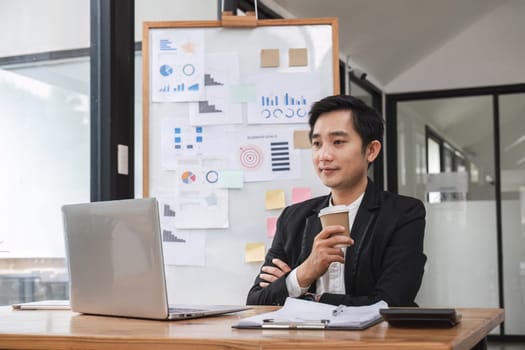 Young Asian businessman working on laptop in office.