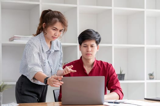 Two businessmen are stressed while explaining workflow on laptop to colleague..