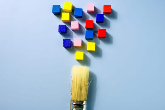 A brush and multi-colored cubes as a symbol of creativity and a non-standard approach.