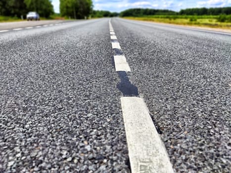 White dotted line on grey asphalt road background. Track in nature and summer landscape