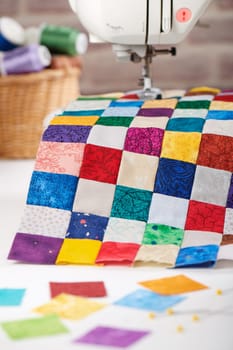 Colorful detail of quilt sewn from square pieces on sewing machine, traditional patchwork