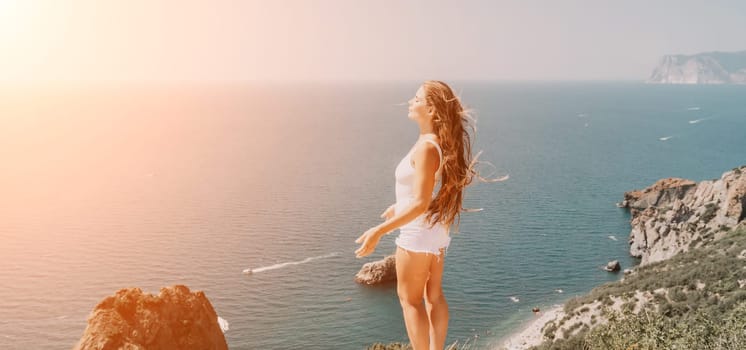 Woman travel sea. Young Happy woman in a long red dress posing on a beach near the sea on background of volcanic rocks, like in Iceland, sharing travel adventure journey