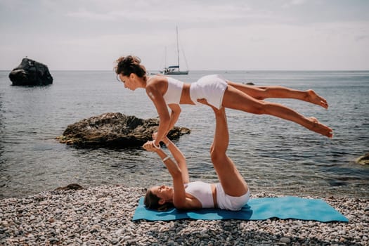 Woman sea yoga. Back view of free calm happy satisfied woman with long hair standing on top rock with yoga position against of sky by the sea. Healthy lifestyle outdoors in nature, fitness concept.