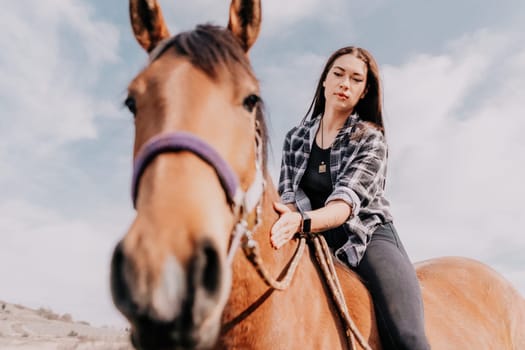 Cute happy young woman with horse. Rider female drives her horse in nature on evening sunset light background. Concept of outdoor riding, sports and recreation.