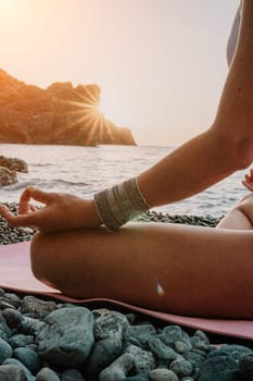 Young woman in swimsuit with long hair practicing stretching outdoors on yoga mat by the sea on a sunny day. Women's yoga fitness pilates routine. Healthy lifestyle, harmony and meditation concept.