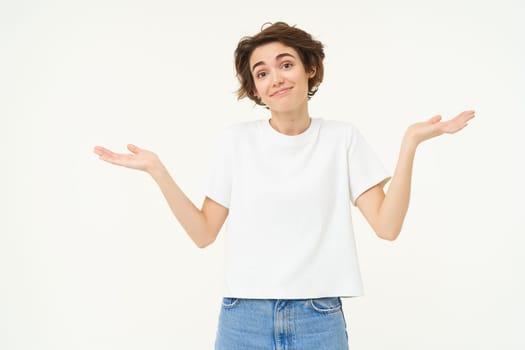 Woman shrugs her shoulders, looks clueless, doesnt know anything, stands confused against white background.