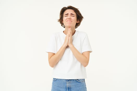 Desperate woman praying, begging for help, pleading, making wish, standing over white background.