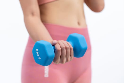 Vigorous energetic woman doing dumbbell weight lifting exercise on isolated background. Young athletic asian woman strength and endurance training session as body workout routine.