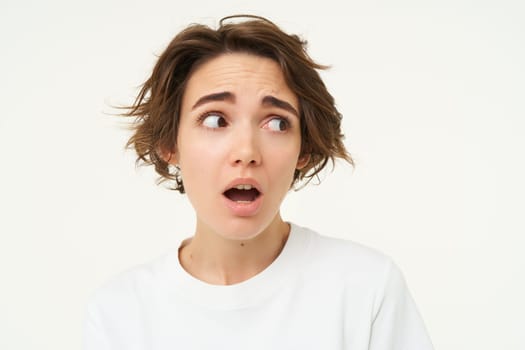 Close up of worried young woman, frowning and looking concerned, standing over white background.