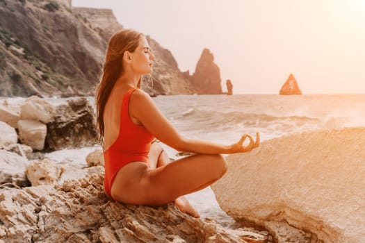 Woman sea yoga. Back view of free calm happy satisfied woman with long hair standing on top rock with yoga position against of sky by the sea. Healthy lifestyle outdoors in nature, fitness concept.