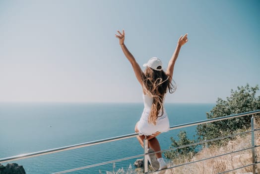 Woman travel sea. Young Happy woman in a long red dress posing on a beach near the sea on background of volcanic rocks, like in Iceland, sharing travel adventure journey