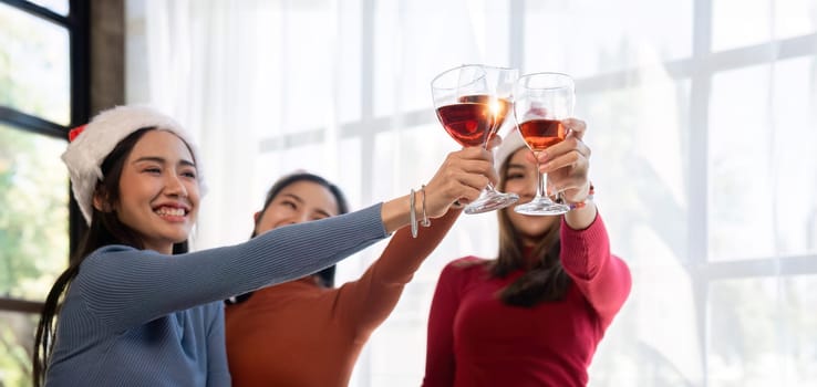 Group of Asian friends together to celebrate Christmas with champagne and eating pizza at home. Joy of holiday party with friends or colleague concept.