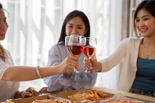 Group of Asian friends together to celebrate Christmas with champagne and eating pizza at home. Joy of holiday party with friends or colleague concept.