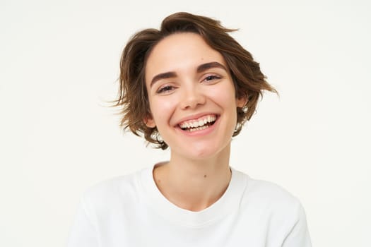 Close up portrait of brunette woman laughing and smiling, express genuine emotions, posing against white studio background.