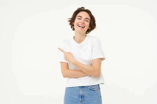 Image of excited woman, pointing finger left, showing advertisement, demonstrating brand banner, standing over white background.