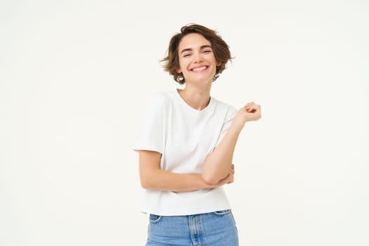 Portrait of carefree woman laughing, posing with confidence, looking self-assured and smiling, standing over white background. copy space