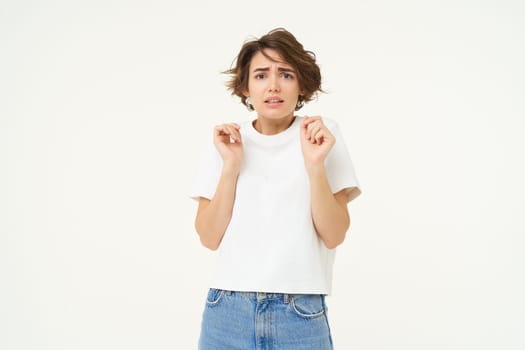 Image of woman with scared face, looks frightened, worried, trembling from fear, isolated against white background.