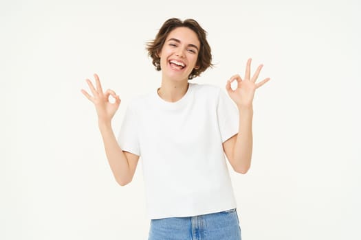 Image of smiling, happy girl shows okay, ok sign, recommending, like and approve something good, standing over white background. copy space